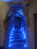 راهروی سنگی با پلههای نورپردازی LED آبی که فضایی غارمانند و مرموز ایجاد کرده است